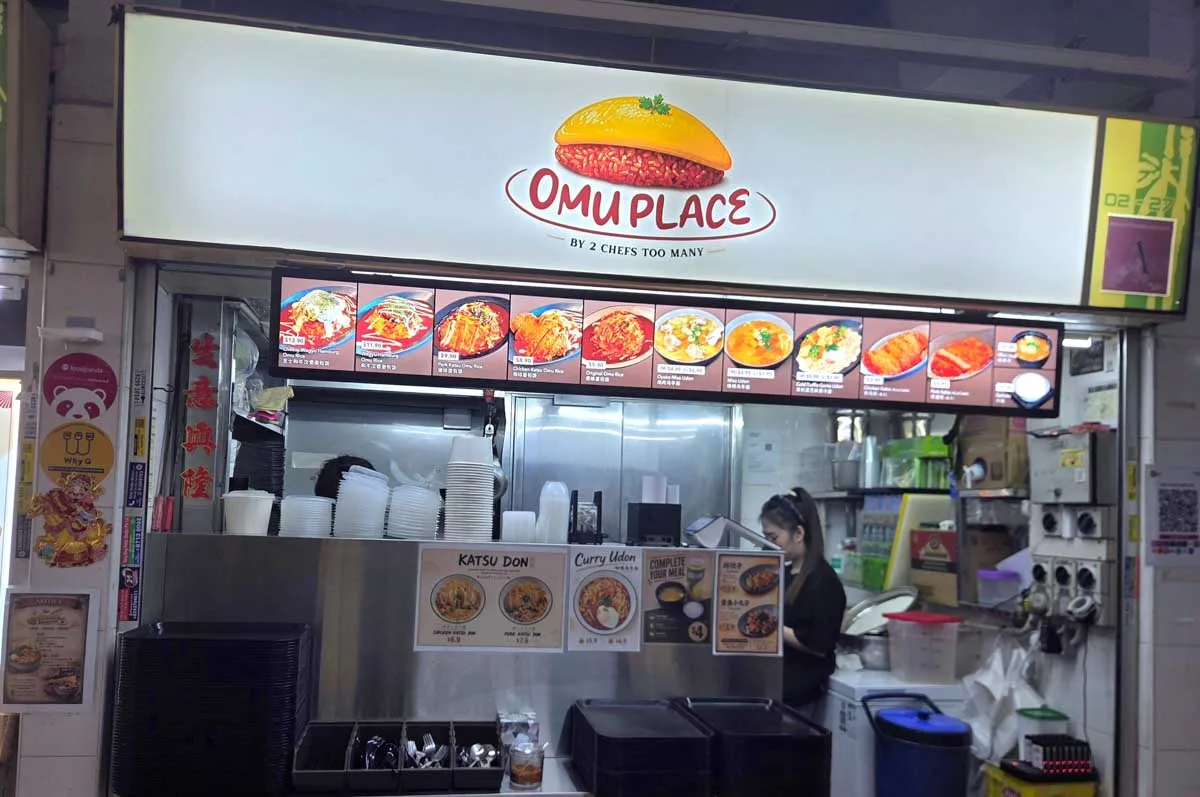 The Omu Place stall front at Hong Lim Market and Food Centre, with its cream lightbox signboard and digital menu strip