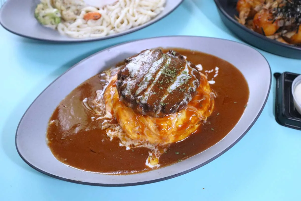 Omu Place's Wagyu Hamburg Omu Rice: a wagyu beef patty over a creamy omelette and rice, in a pool of glossy demi-glace